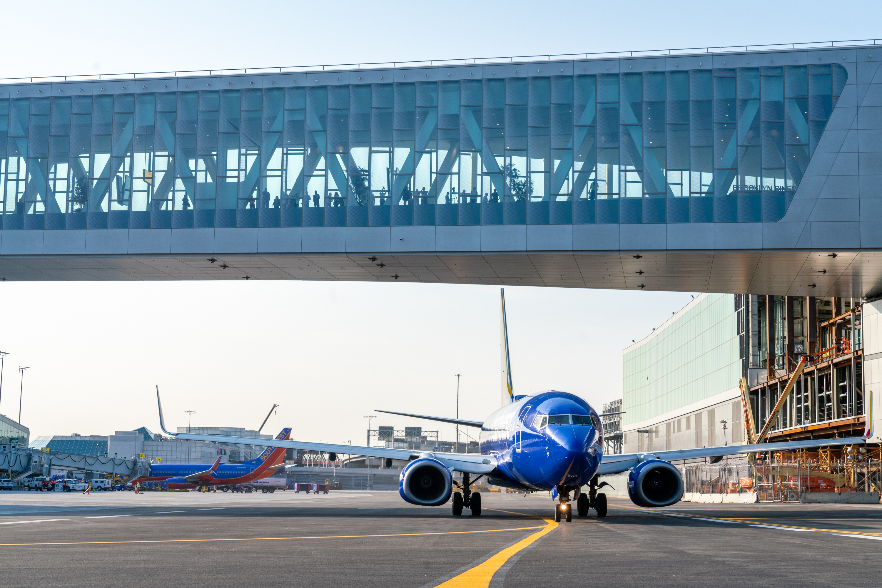 Southwest aircraft taxis under an elevated pedestrian walkway at LaGuardia Terminal B.